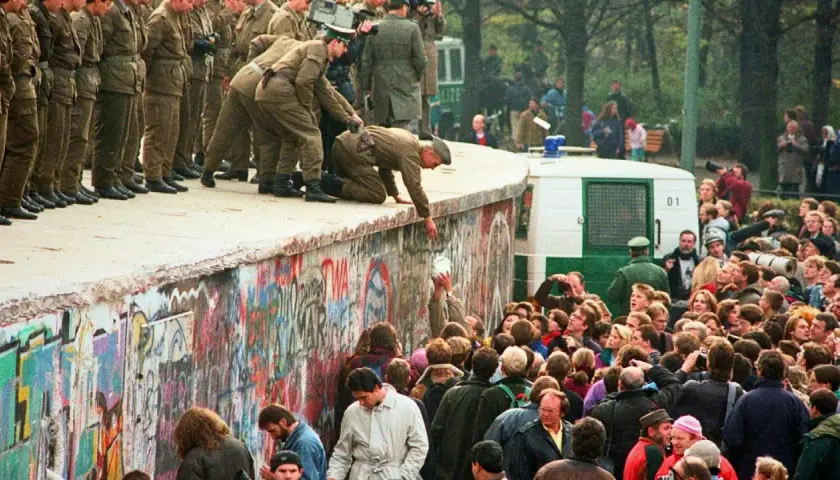 Menschen feiern die Wiedervereinigung Deutschlands am Berliner Mauer. Soldaten helfen Menschen über die Mauer. Eine Zusammenfassung der Freude und des Wandels.