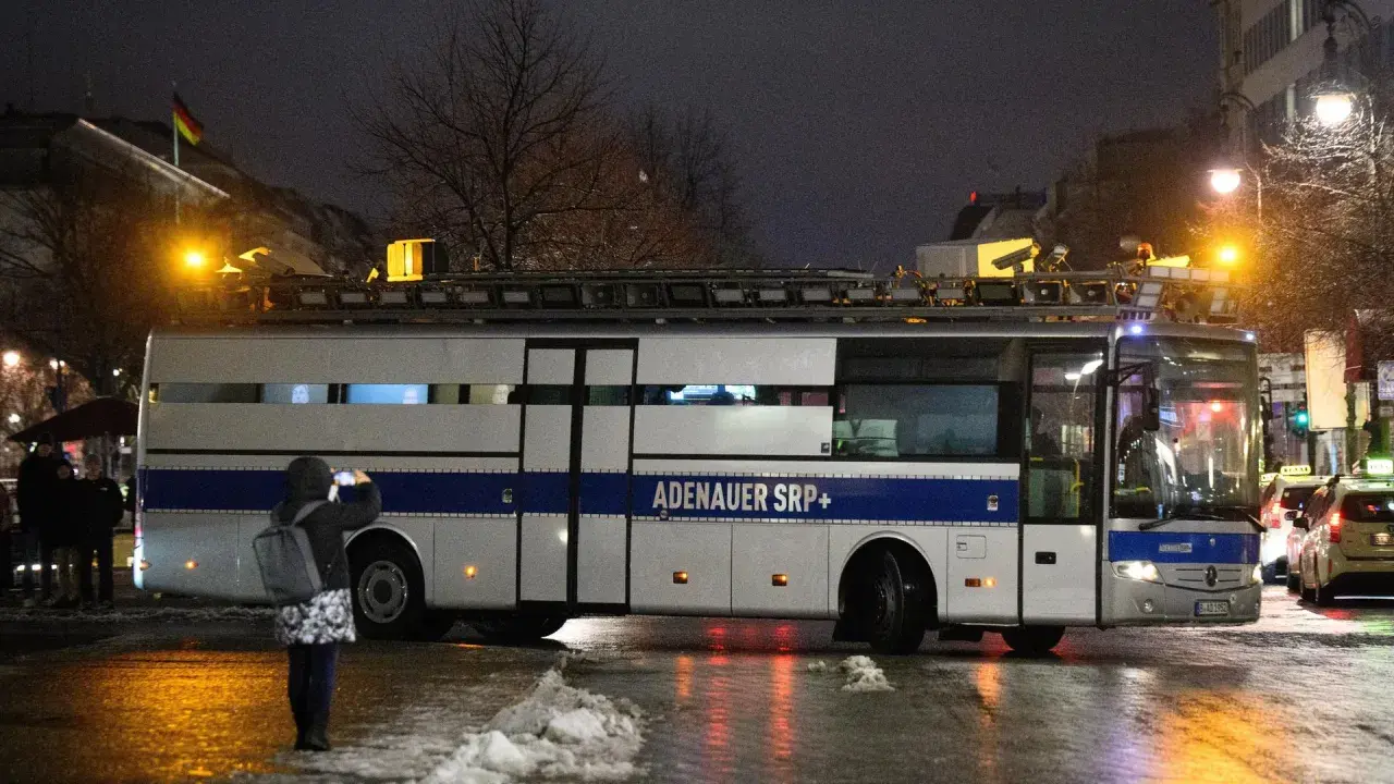Ein Bus mit der Aufschrift "ADENAUER SRP+" steht im Dunkeln. Eine Person fotografiert ihn.