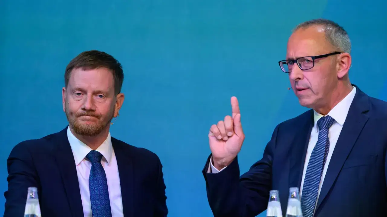 Zwei Männer im Anzug, einer mit Bart, der andere mit Brille und erhobenem Zeigefinger, diskutieren. Möglicherweise geht es um civey sachsen.