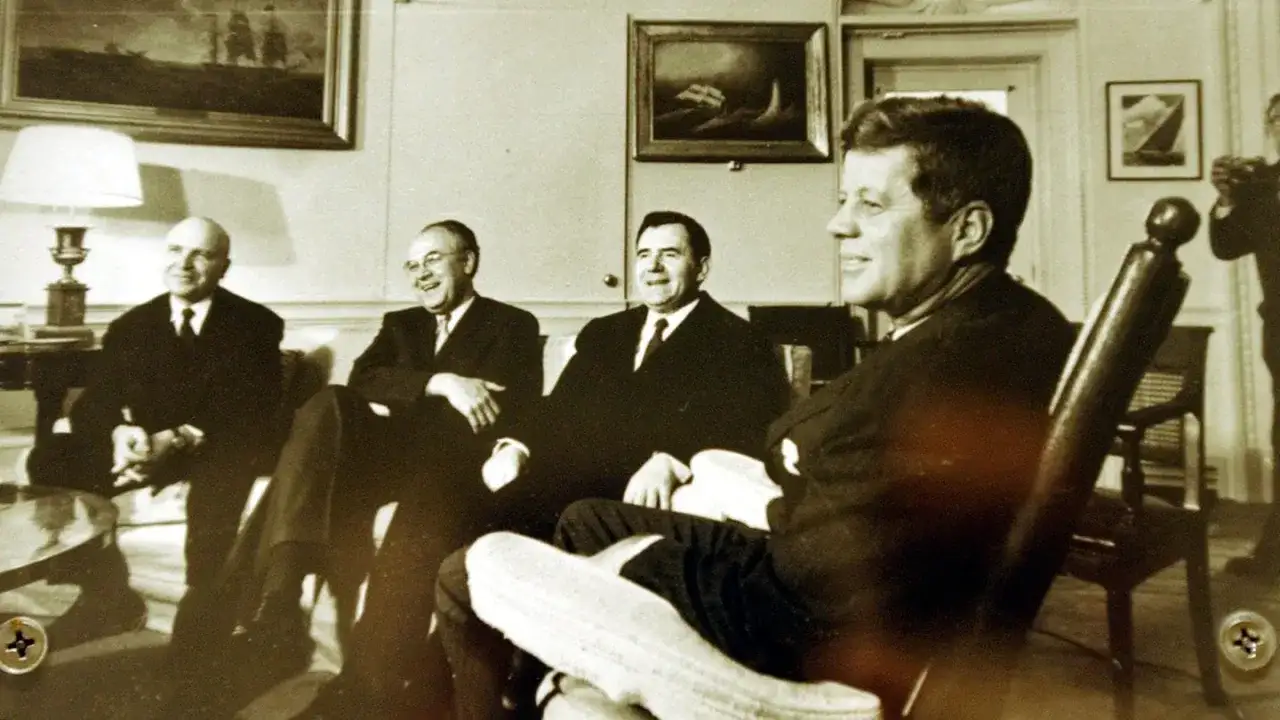 John F. Kennedy und Berater besprechen die kubakrise folgen. Vier Männer in Anzügen sitzen in einem Raum mit Gemälden.
